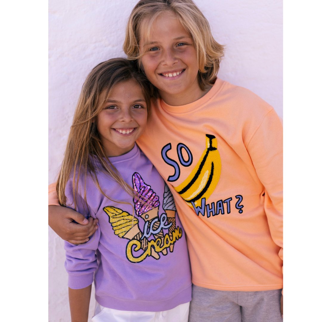 Mädchen mit Sweatshirt in beige und Corgi Stickerei stehend