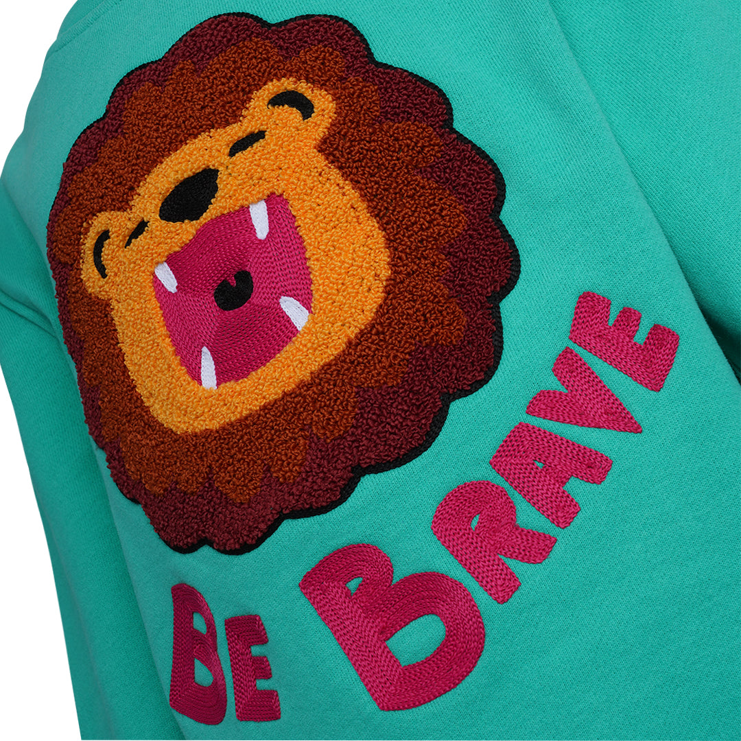 Detailansicht: Hochwertige 3D-Löwen Stickerei auf dschungelgrünem CHIO MI Kindersweatshirt – Kontrastreiche Details – Close-up lion embroidery detail on green – Détail de broderie lion de haute qualité sur vert jungle.