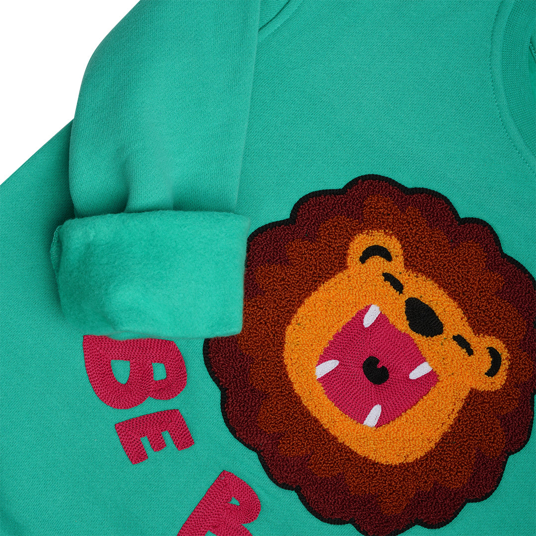 Detailansicht: Hochwertige 3D-Löwen Stickerei auf dschungelgrünem CHIO MI Kindersweatshirt – Kontrastreiche Details – Close-up lion embroidery detail on green – Détail de broderie lion de haute qualité sur vert jungle.