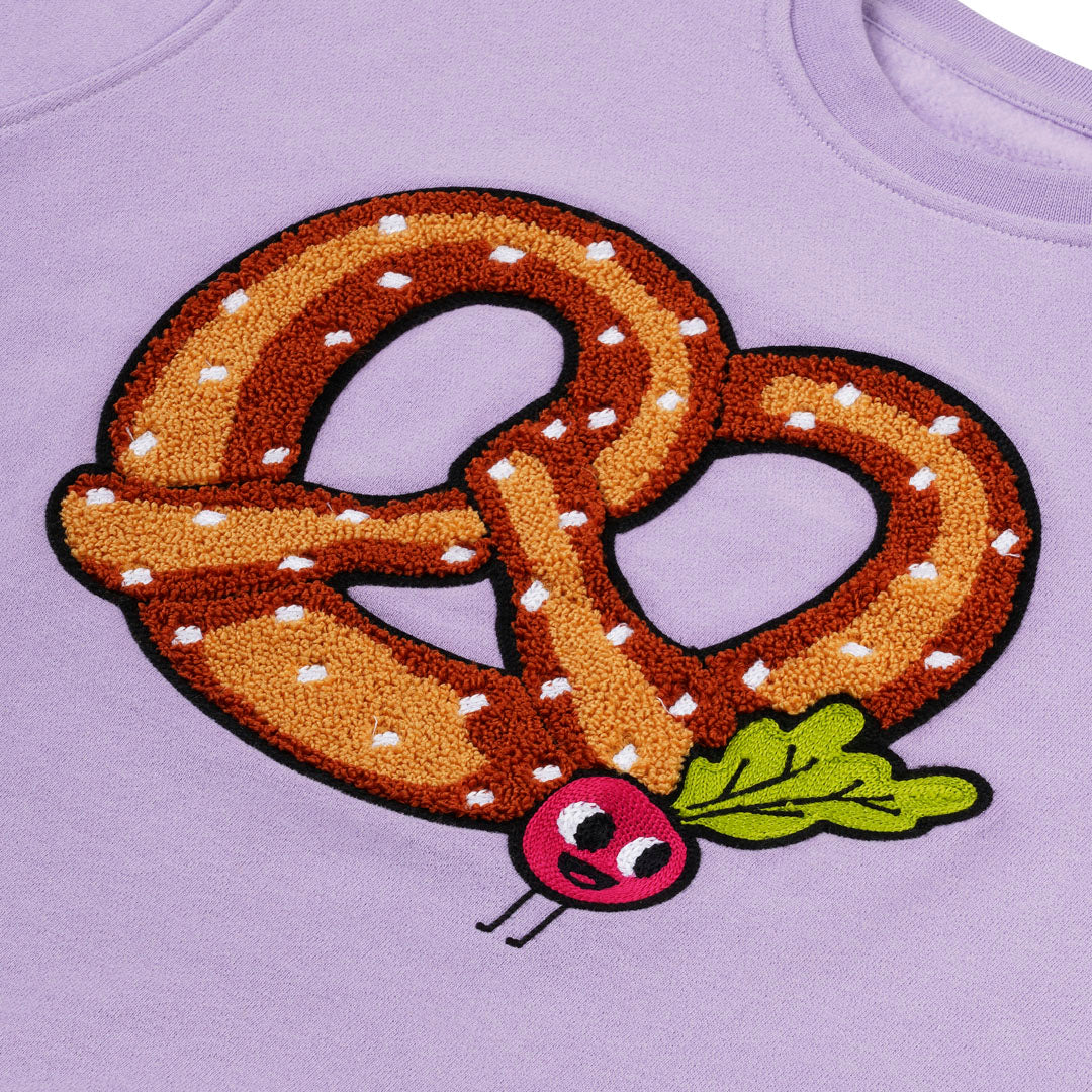 Detailansicht: Hochwertige Stickerei Brezel mit kleinen Radieschen auf lavendelfarbenem CHIO MI Kindersweatshirt – Close-up pretzel and radish embroidery detail – Détail de broderie bretzel et radis de haute qualité.
