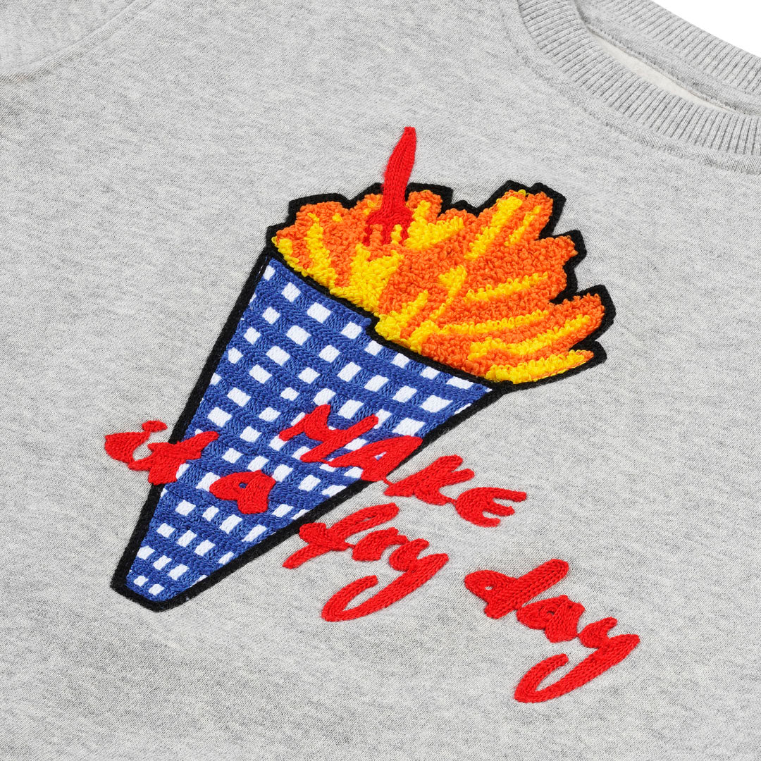 Detailansicht: „Make it a Fryday“ Slogan und hochwertige Pommes-Tüten Stickerei auf CHIO MI Sweater – Close-up French Fries embroidery detail – Détail de broderie frites de haute qualité.