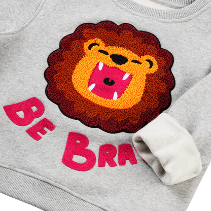 „Be Brave“: Kind im CHIO MI Löwen Sweatshirt – Das ideale Mutmacher-Geschenk für die Einschulung oder den Kindergarten – Kids wearing "Be Brave" lion outfit – Enfant portant le sweat lion "Be Brave" comme cadeau de rentrée scolaire.