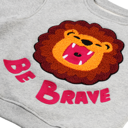 Detailansicht: Hochwertiger „Be Brave“ Schriftzug und detailreiche Löwen-Stickerei auf CHIO MI Sweater – Close-up "Be Brave" lion embroidery – Détail de broderie lion et texte "Be Brave" de haute qualité.