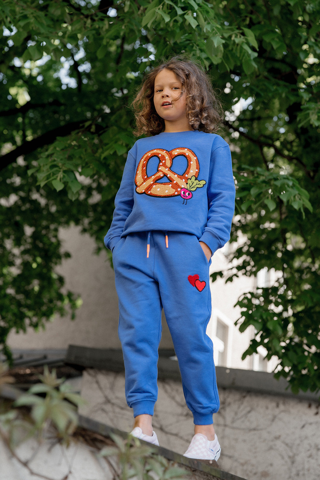 Oktoberfest Tradition: Kind im CHIO MI Brezel Sweatshirt Royal Blue – Perfekt zur Lederhose oder Jeans – Kids wearing traditional Bavarian pretzel outfit – Enfant portant le sweat bretzel bleu pour la fête de la bière.